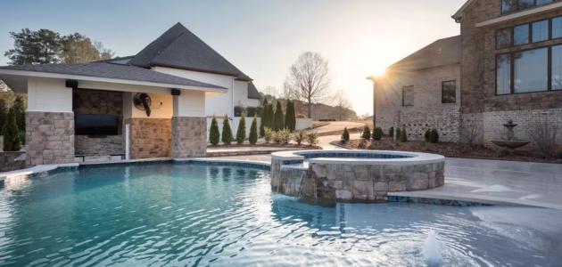 sun rising over freeform pool with above ground spa and bubbler fountain