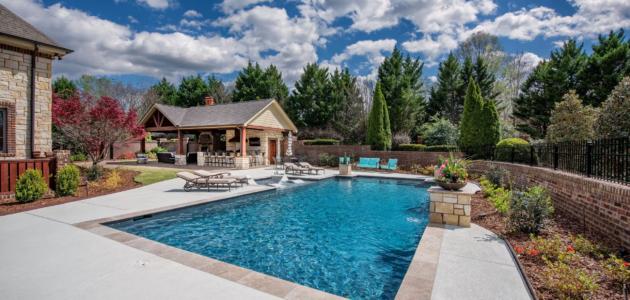 geometric pool in a backyard with tanning ledge and flowers