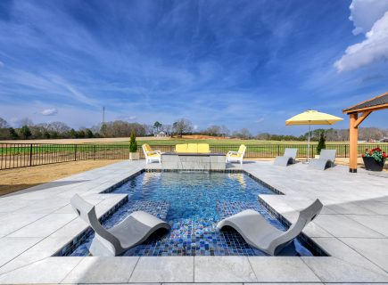 inground pool with sun loungers in backyard