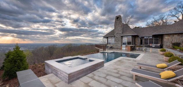 a square spa next to geometric pool looking over a view below